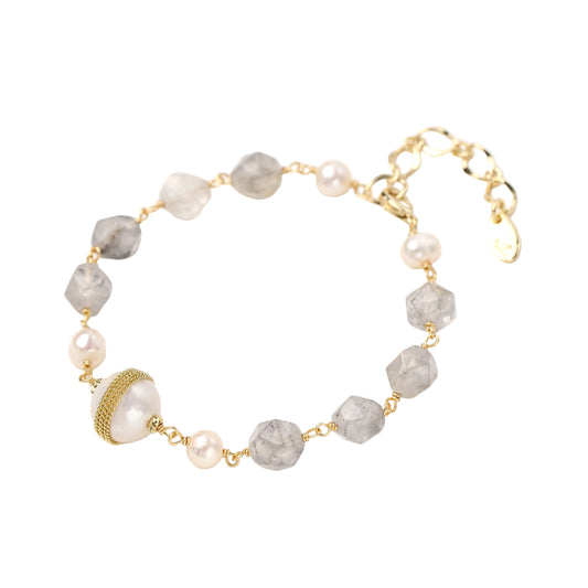 Bracelet with cloudy quartz beads, freshwater pearls, and gold-wrapped baroque pearl centerpiece on white background.